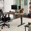 Electric Standing Desk 60x30 in reclaimed wood finish in lowered position in an home office setting.