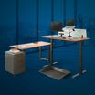 Electric Standing Desk and benching table in office with large windows
