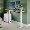 light wood and white standing desk in office in raised position