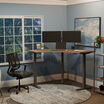 A clean and modern home office setup with a walnut command center standing desk, dual monitors, mesh ergonomic chair, and blue walls accented by large windows and abstract wall art.
