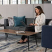 woman sitting on the three aspire sofa while working on her laptop