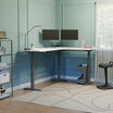 white finish l shape electric standing desk in a raised position in the corner of a workspace