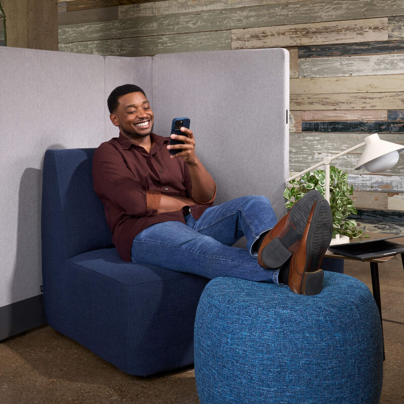 man sitting on chair with his feet up on an ottoman while looking at his phone image number null