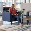 woman sitting in a navy chair working in an open office setting 