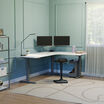 white finish l shape electric standing desk in a lowered position in the corner of a workspace