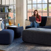 woman sitting on a couch working on her laptop in an open office