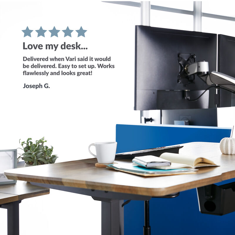 electric standing desk in an office setting with a customer review rating saying love my desk delivered when vari said it would be delivered easy to setup works flawlessly and looks great by joseph  image number null