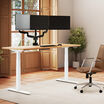 Solid Wood Electric Standing Desk with a white oak top and silver frame in a bright home office, fitted with a triple-monitor arm holding three monitors, with a tan office chair beside it.