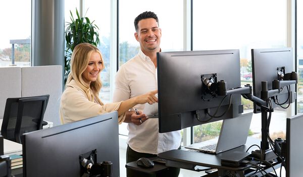 two individuals working at a workspace together 