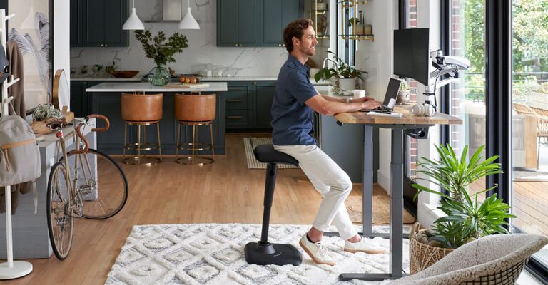 vari electric standing desk and active seat being used in a home setting