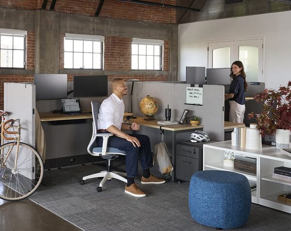 man and woman talking in an office over a cubicle wall
