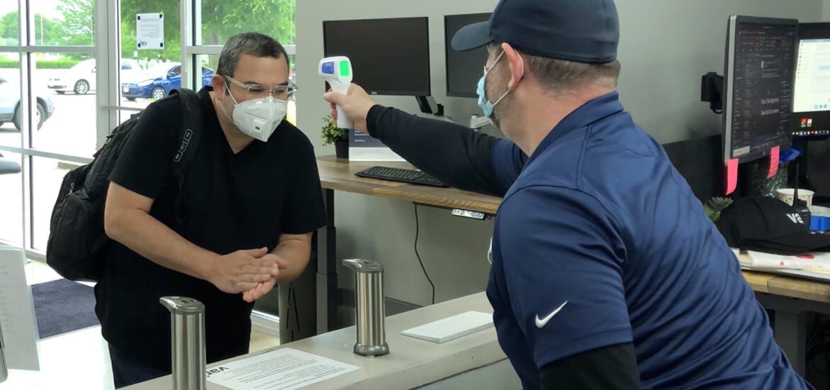vari receptionist taking the temperature of an arriving employee