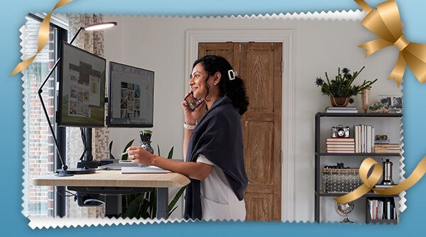 person sitting in a vari task chair with headrest next to a vari electric standing desk