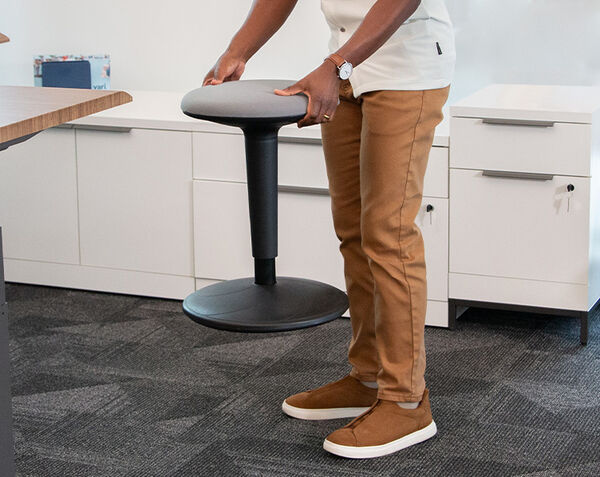 individual picking up the balance stool