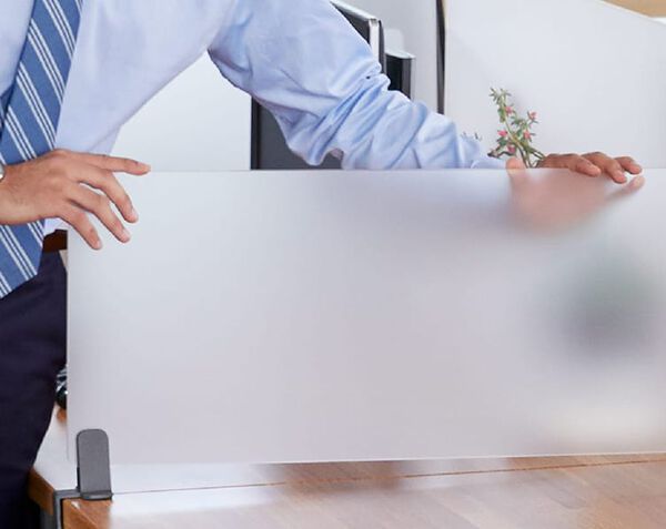 Professional attaches acrylic privacy panel to a table 