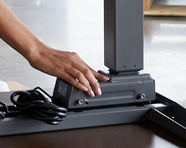 Individual is assembling the Electric Standing Desk 48x30 by locking the legs of the desk into place with one hand