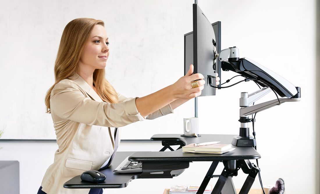 Professional adjusting monitor and monitor arm on VariDesk Converter in office