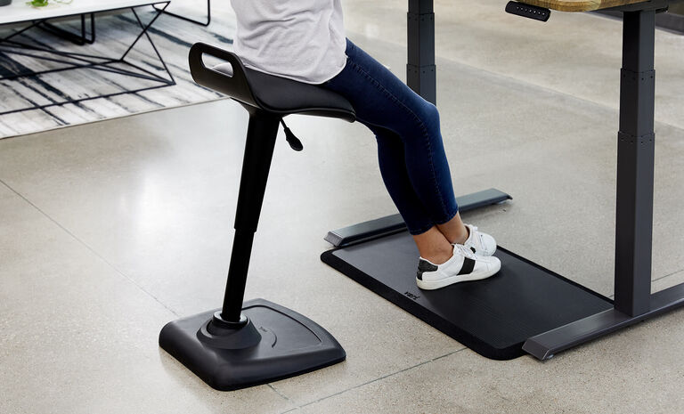 professional seated on active seat while using standing mat