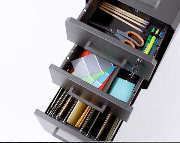 all three drawers open and seen from above, the bottom holds files and the top two drawers hold office supplies.
