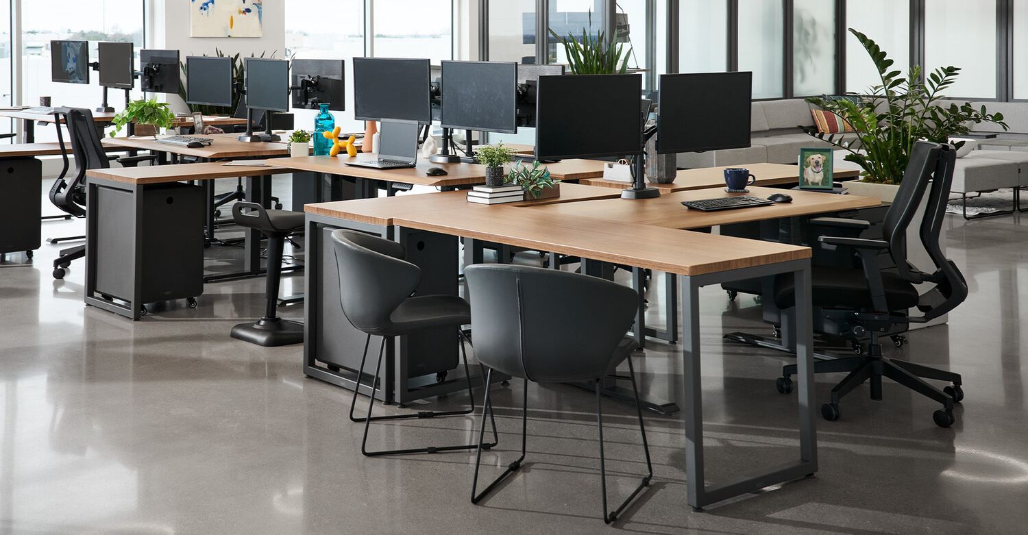 vari electric standing desk and table in a cubicle