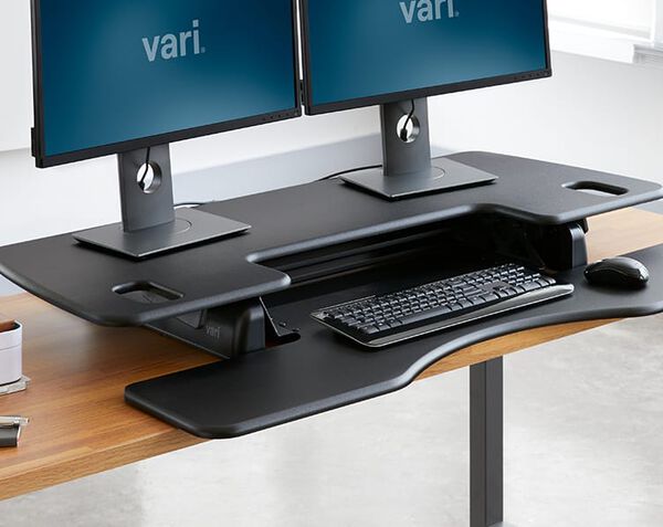 Desk converter lowered to a sitting position on an exsisting desk in an office