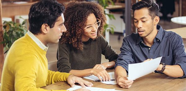 three individuals at conference table discussing business
