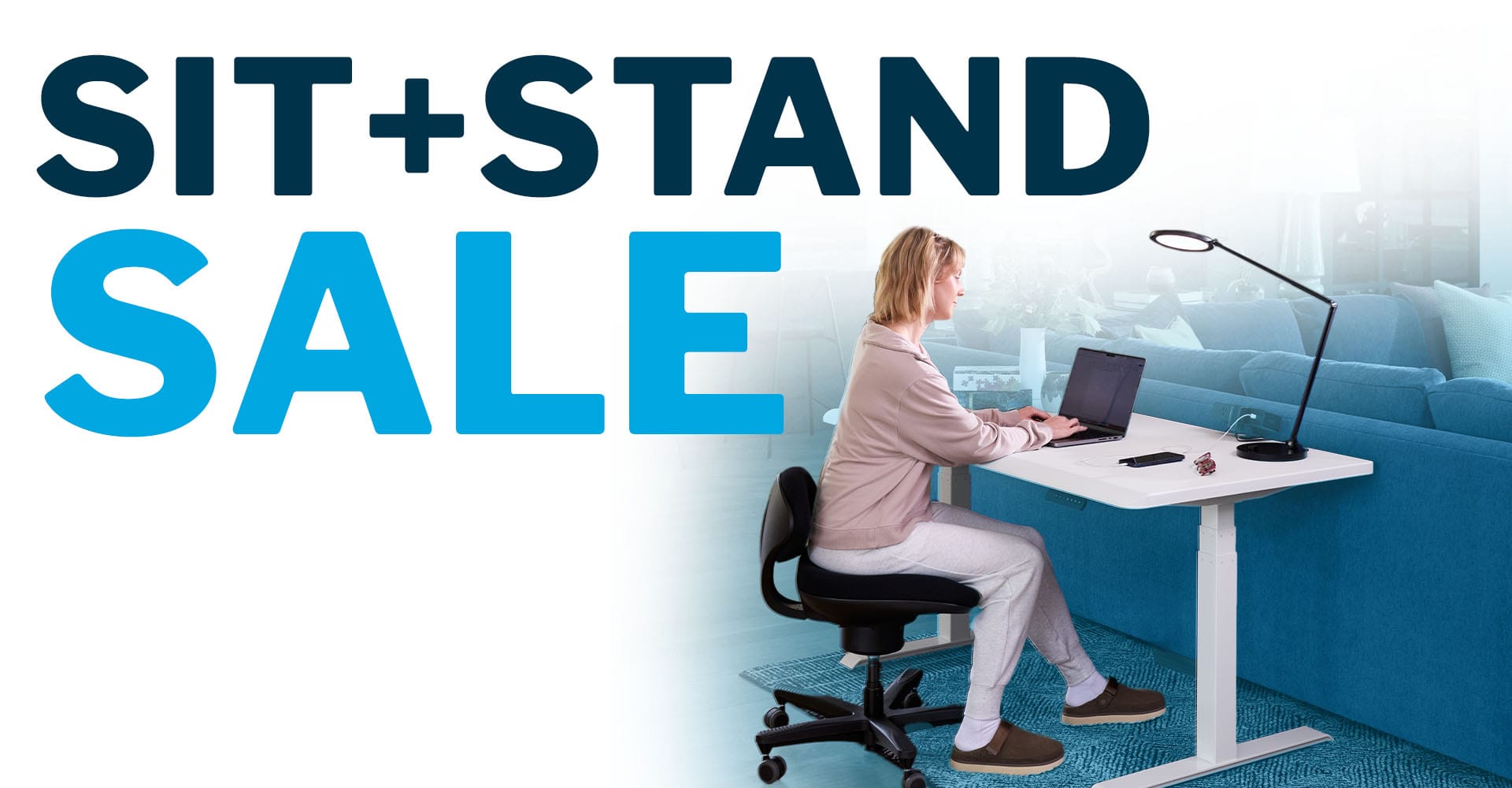 individual working at an electric standing desk and dual monitor arms