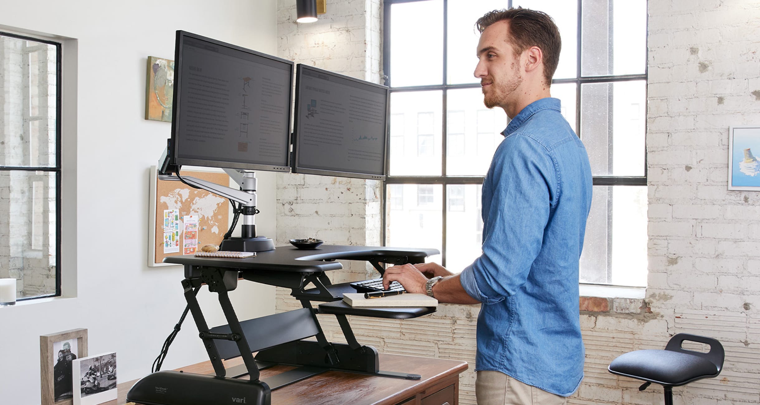 a man standing working at a standing desk converter in an office