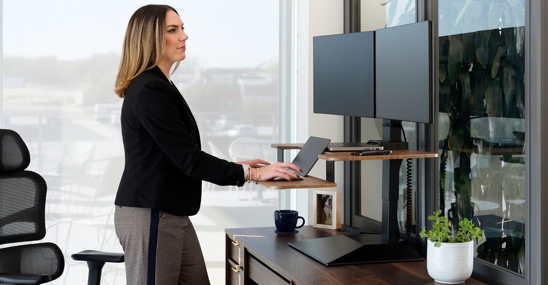 individual working at an electric standing desk and dual monitor arms
