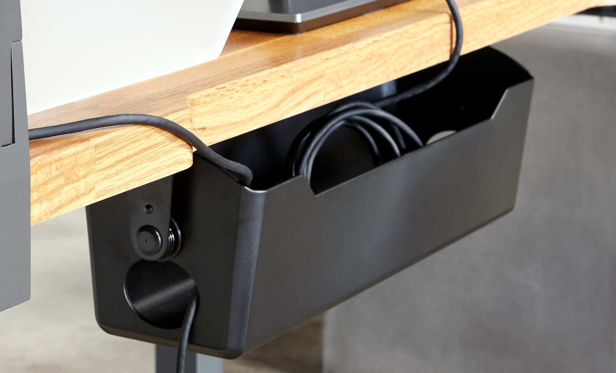 black cable management tray attached to desk in office setting