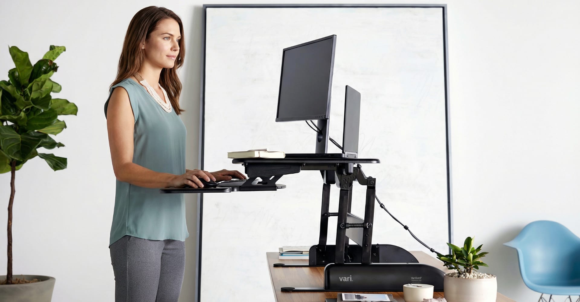 individual working at an electric standing desk and dual monitor arms
