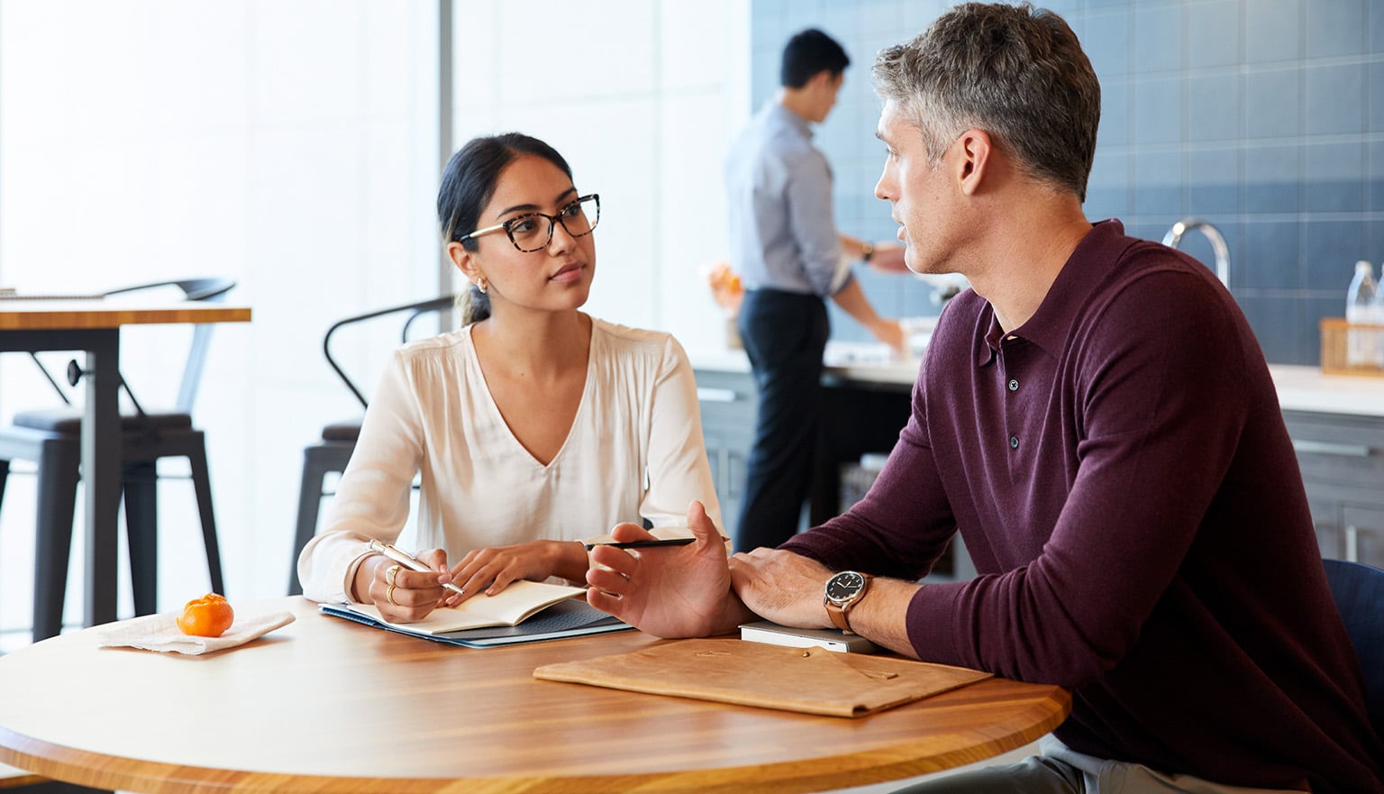 professionals enjoy breakroom conversation while seated at a round table