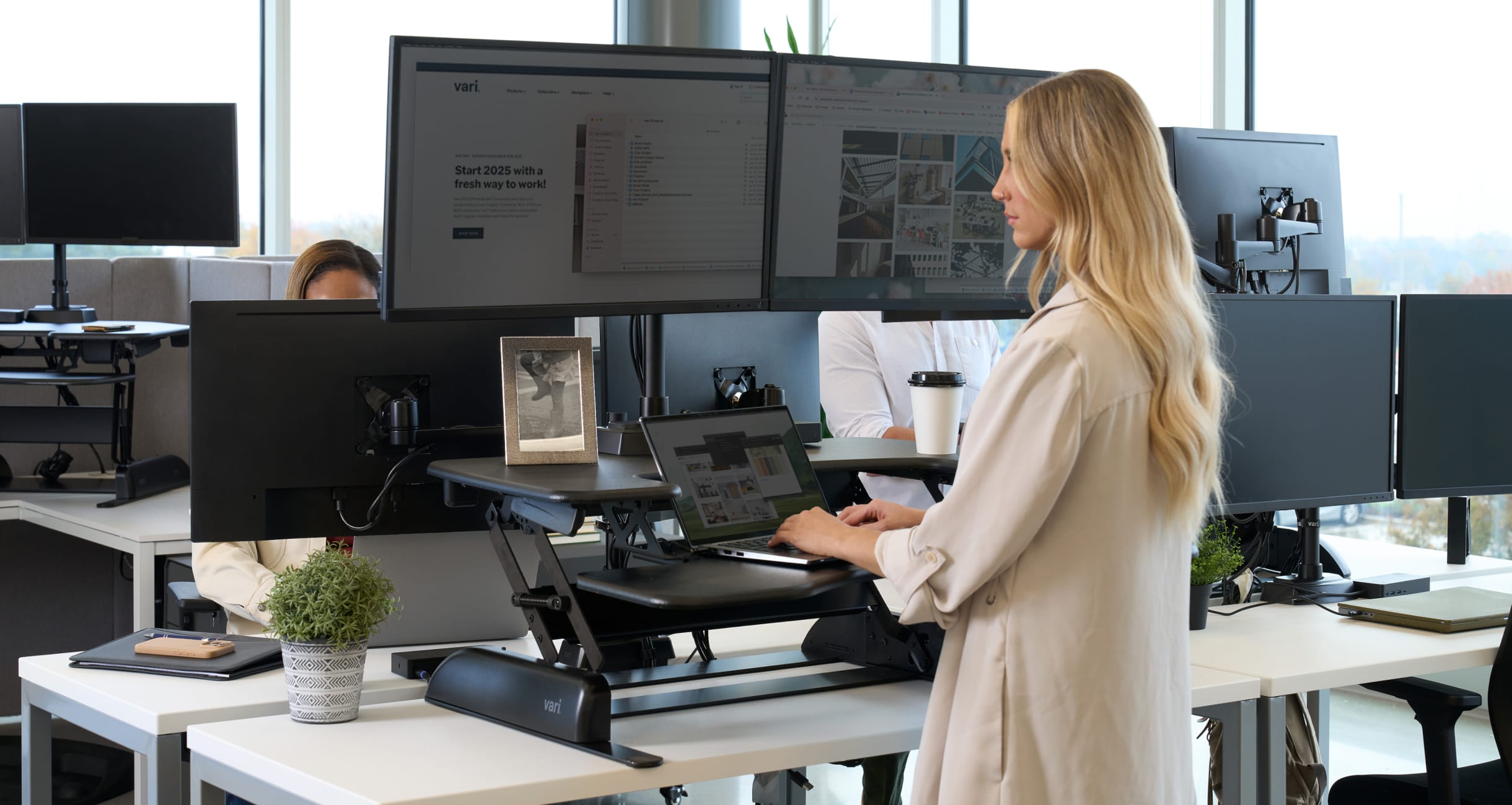 individual working at an electric standing desk and dual monitor arms