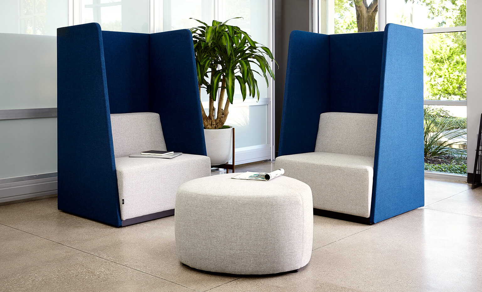 two high back chairs appear with a small ottoman in an office environment