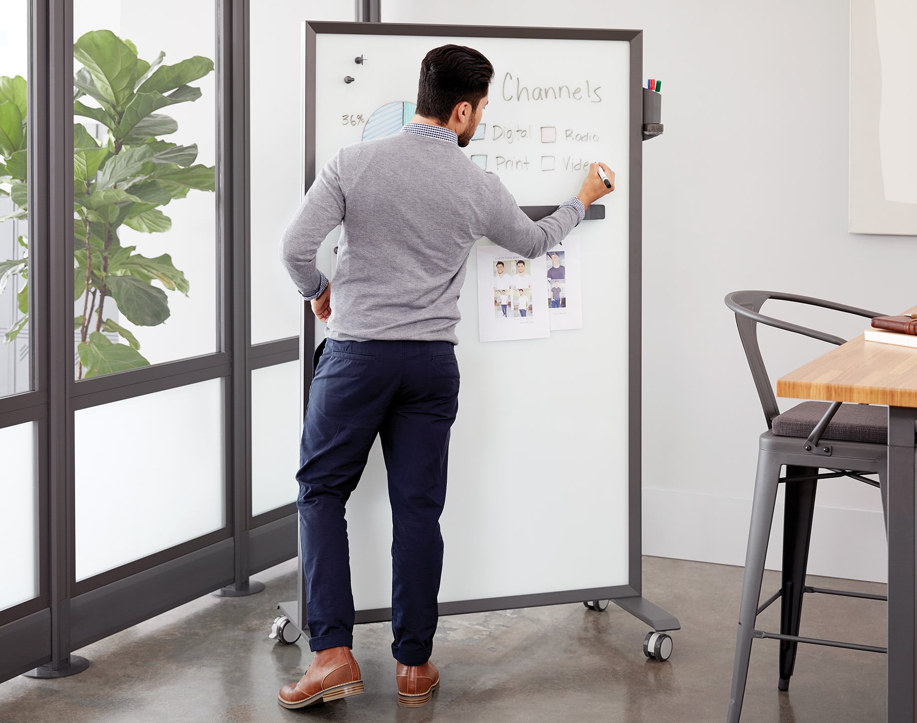 man writes on a markerboard to present data in a meeting
