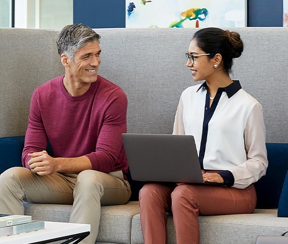 two professionals sitting on couch with laptop