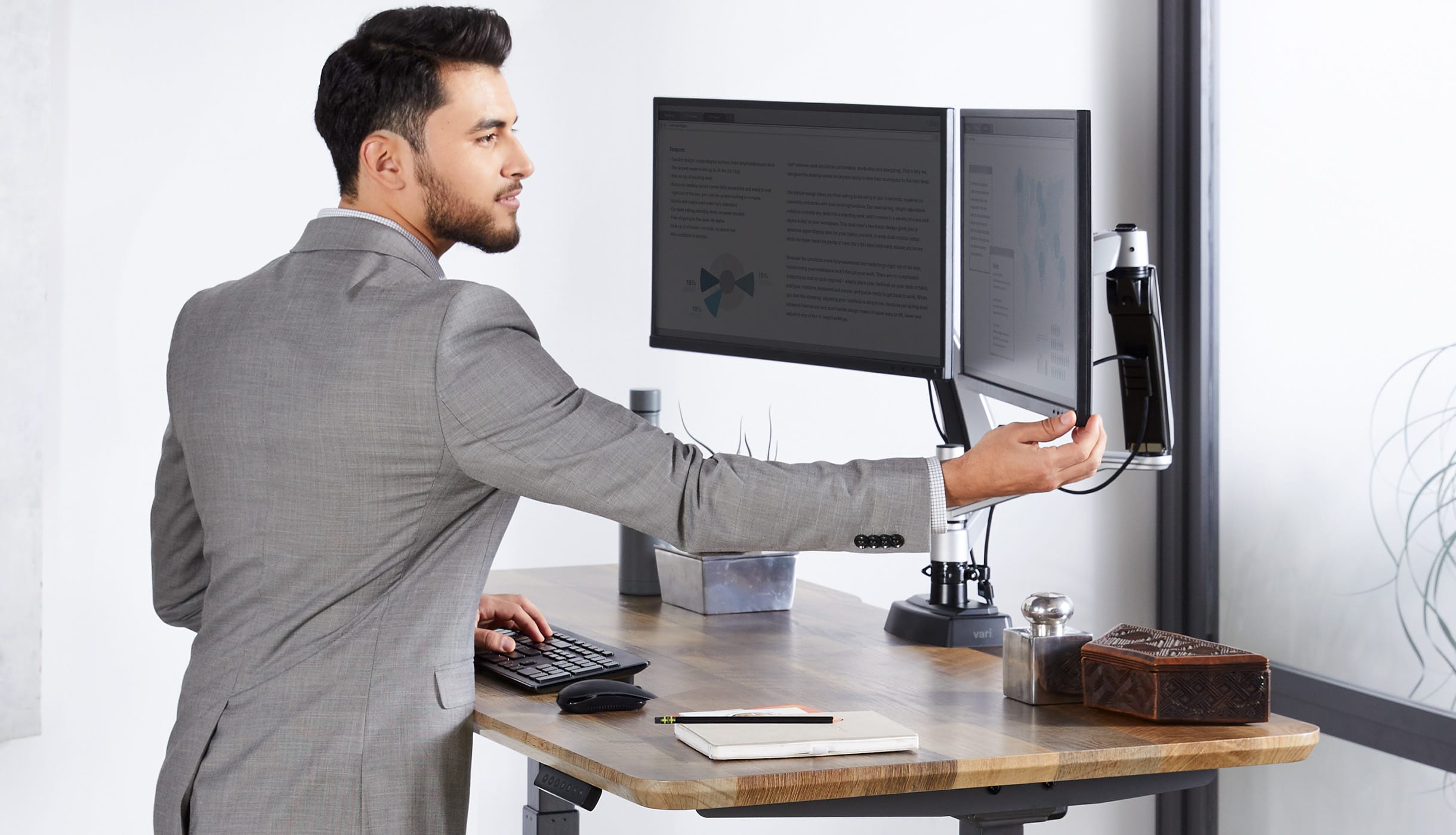 professional adjusts his monitors easily with one hand to ensure it's properly placed for the best posture.