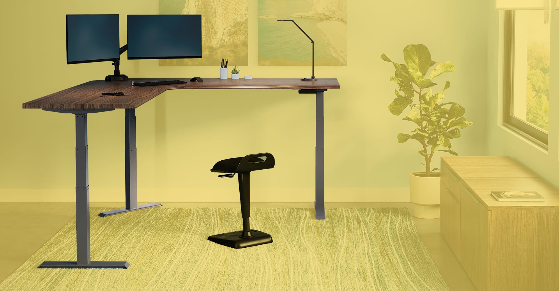 L shape electric standing desk with monitors and a stool in an open home office setting