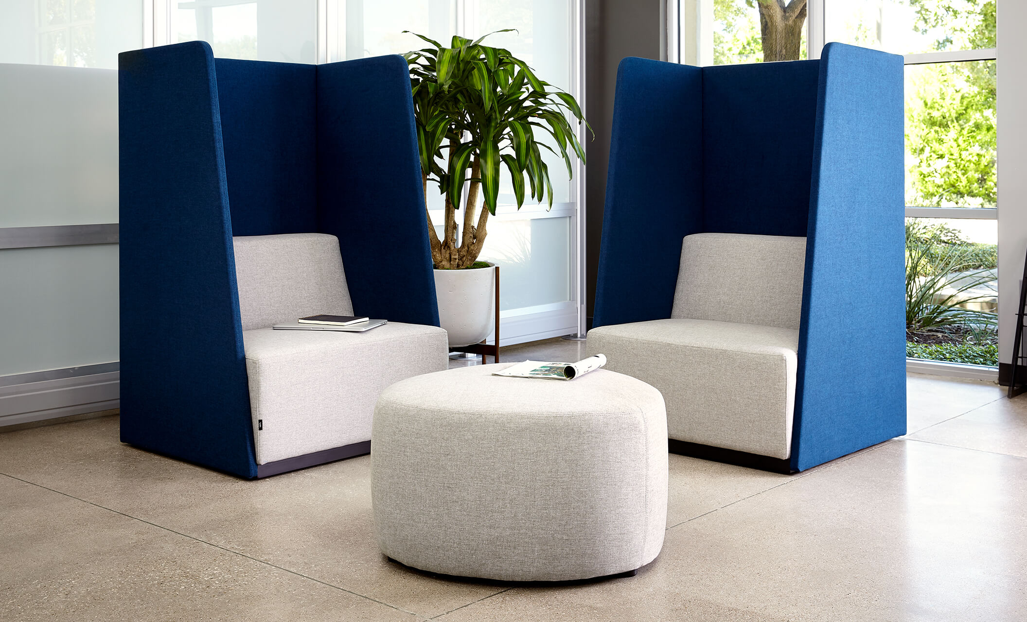 two high back chairs appear with a small ottoman in an office environment