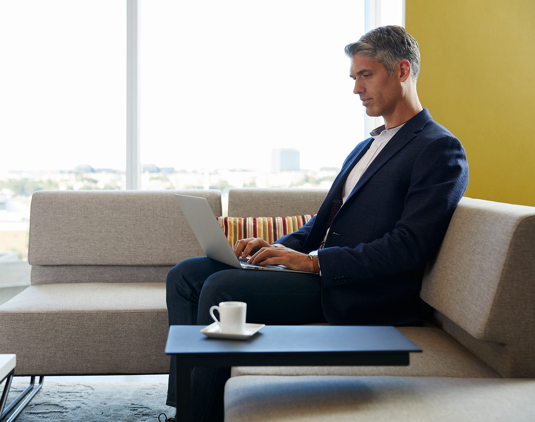 professional sitting on couch with cup of coffee on an accent table