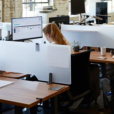 professional works in office setting with privacy panels to increase distance
