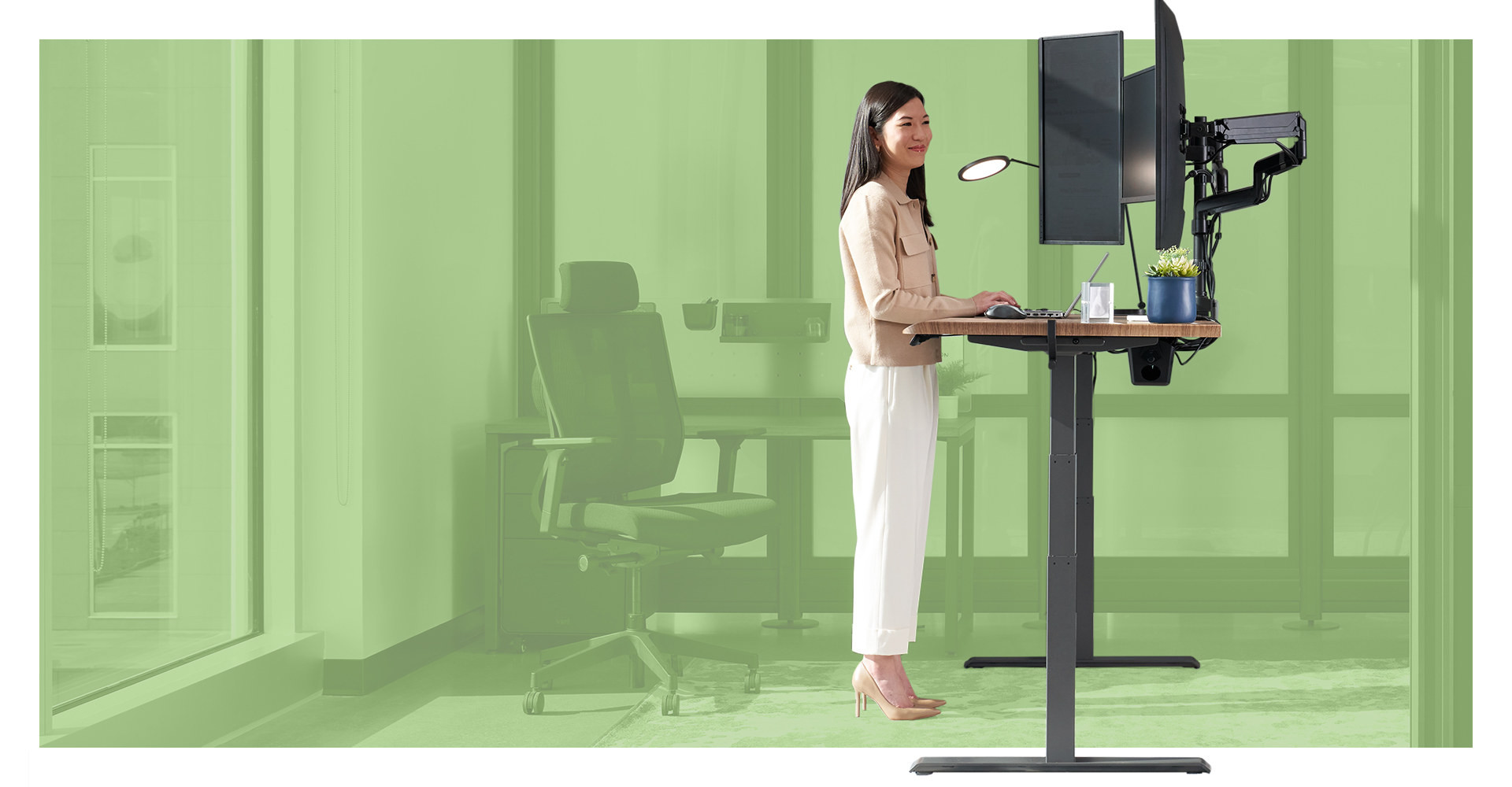 individual working at an electric standing desk in an open office