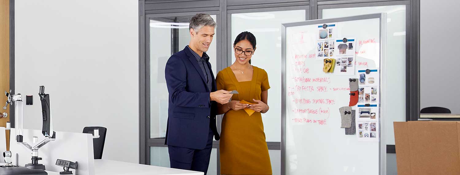 two individuals standing side by side looking at textiles in an office